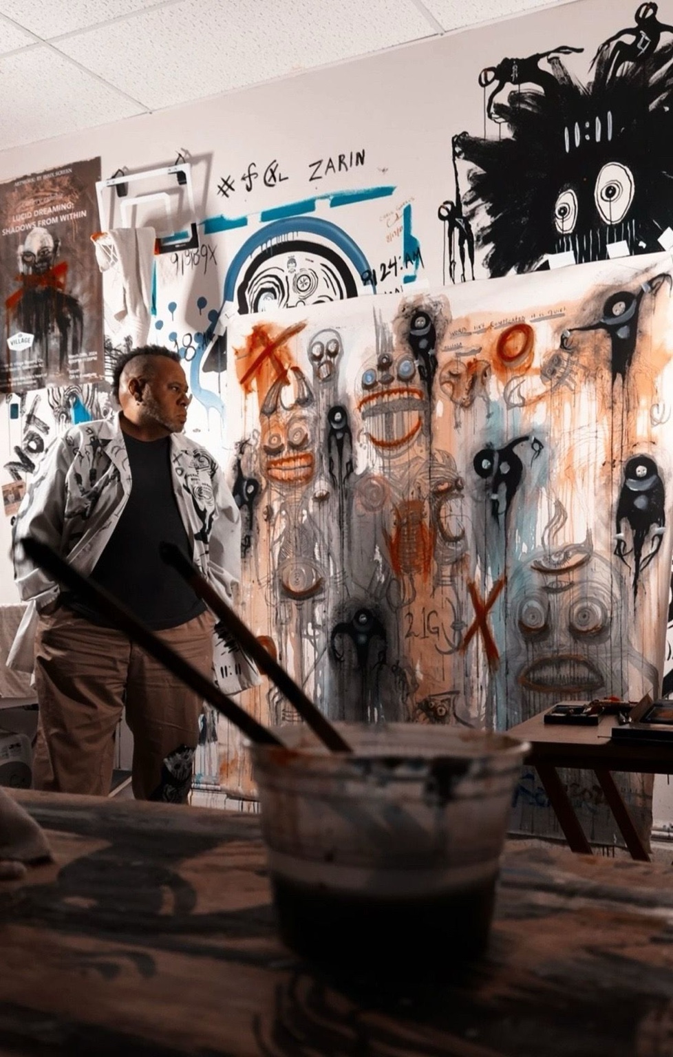 Artist Irrix Screen standing inside White Sky Gallery among his original paintings